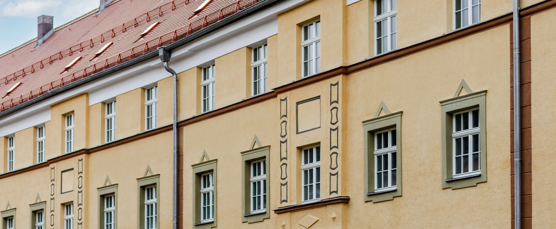 Wohnblock Nahaufnahme von Fassade it Fenster. Fenster haben Ornamente als Gestaltung, manche in grün andere haben in der Architektur eine Gestaltung.