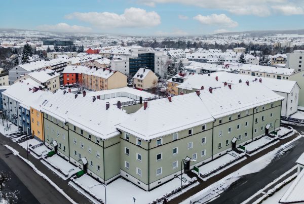 Ansicht Wohnblock aus Vogelperspektive, grüne Fassade, 3 Stockwerke mit 5 Eingänge.